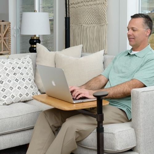 Image of man using Omni Tray for his laptop while sitting on couch.