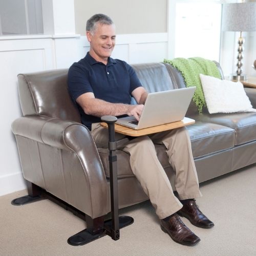 Image of a man using his laptop on the couch with the Omni Tray in front of him.