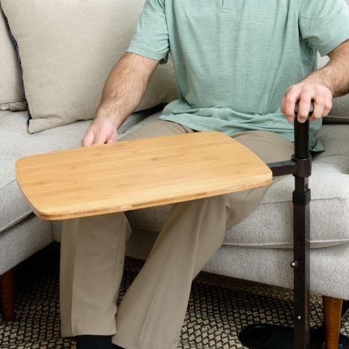Image of man sitting on couch and swiveling Omni Tray from him.
