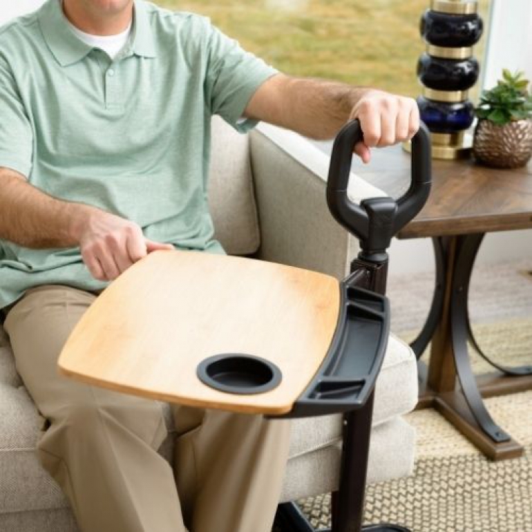 Man swiveling tray away from himself while sitting on the couch.