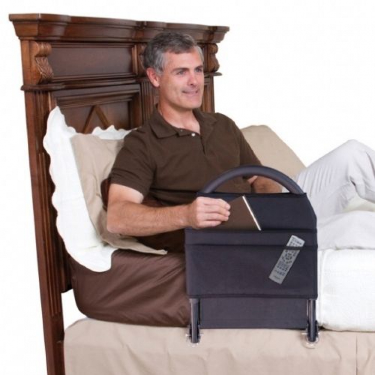 Image of man lying on bed and taking book out of Bed Rail Advantage pouch.