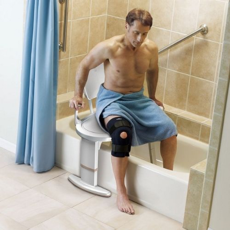 Man using transfer bench to transfer himself into tub.