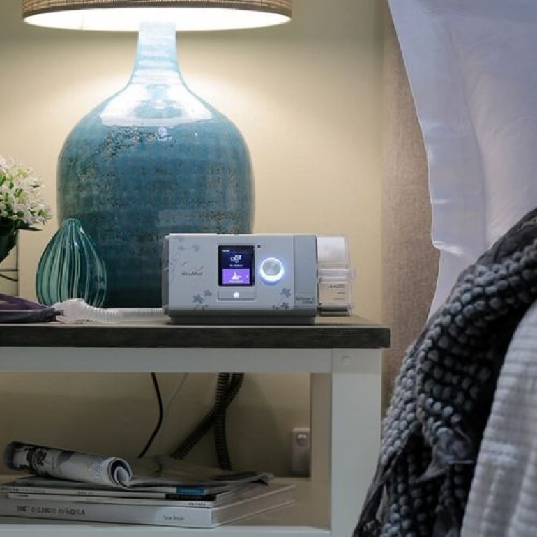 Image of the ResMed AirSense 10 AutoSet For Her on bedside table.