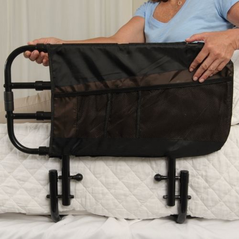 Woman sitting in bed and holding the Stander EZ Adjust Bed Rail.
