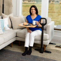 Woman eating and drinking while sitting on the couch with Assist-A-Tray in front of her. thumbnail
