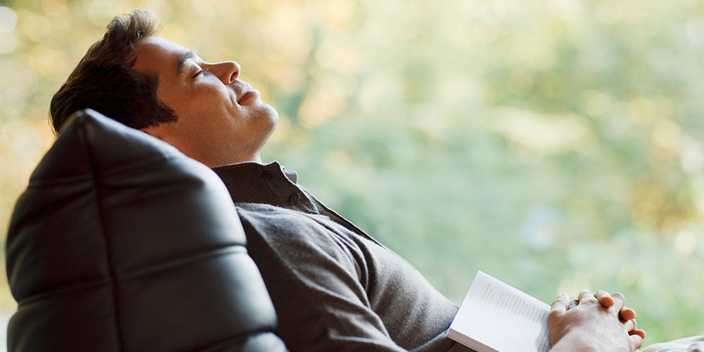 A man sleeping in a recliner who could benefit from using sleep apnea or oxygen therapy equipment